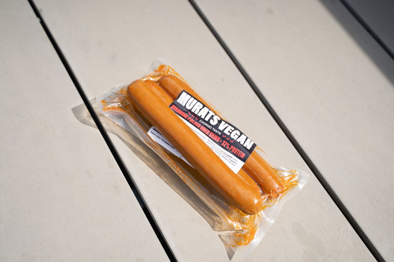 Denne pølse fra Murats Vegan var krydret med chili, hvorfor den var en smule spicy at spise, som den eneste i testen. Foto: Thomas Schønning. Stor pølse ligger oven på pakke ude i sollys. Pølsen er let fedtet i noget rødligt stads.